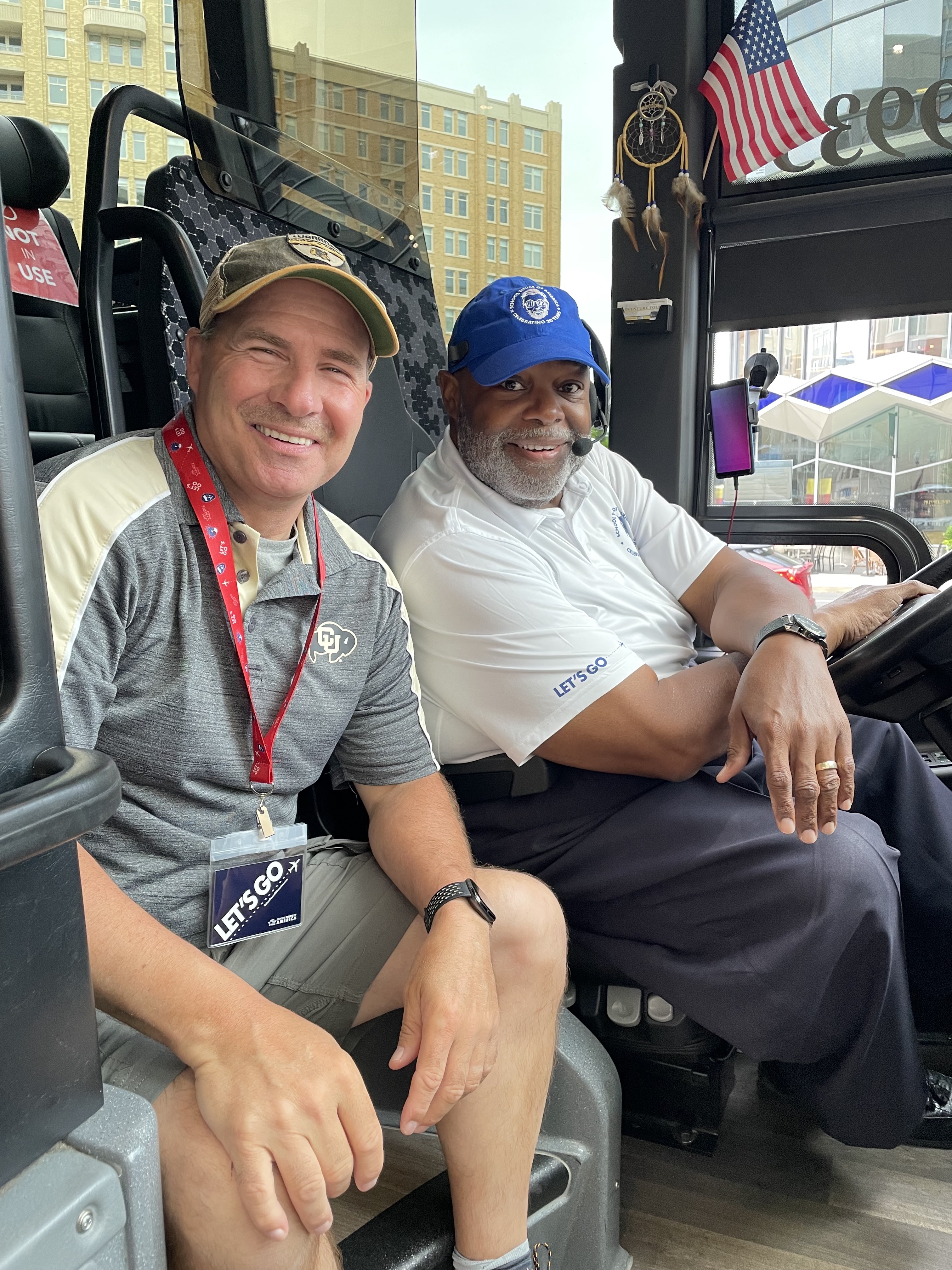A teacher sits smiling with their local Washington, DC bus driver about to tour.